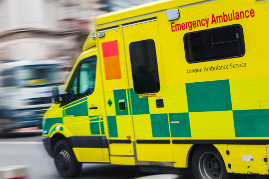 Photo of a speeding ambulance with a blurred background.