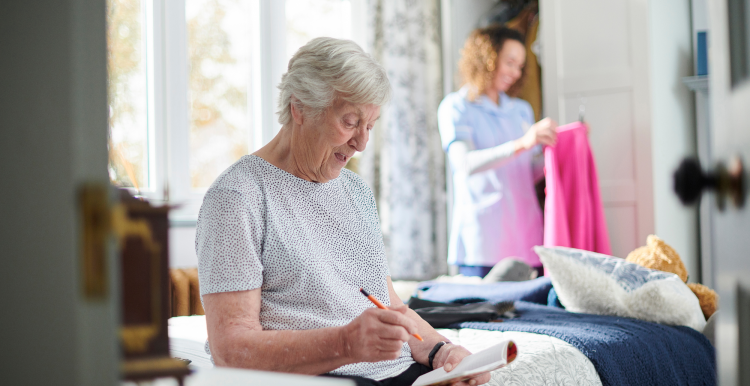 A carer helping an older woman in her home.