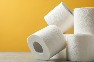 Four rolls of toilet paper stacked against a yellow background.