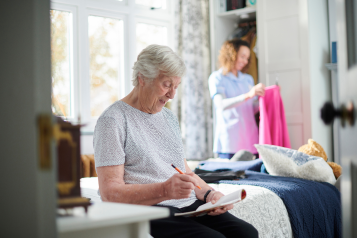 A carer helping an older woman in her home.