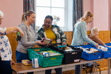 A group of women looking at donations that have been given to a foodbank.