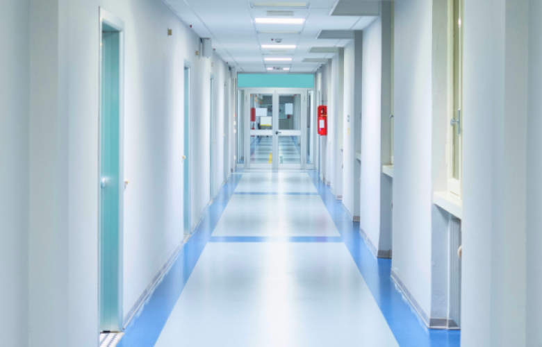 A blue and white hospital corridor with rooms off to each side.